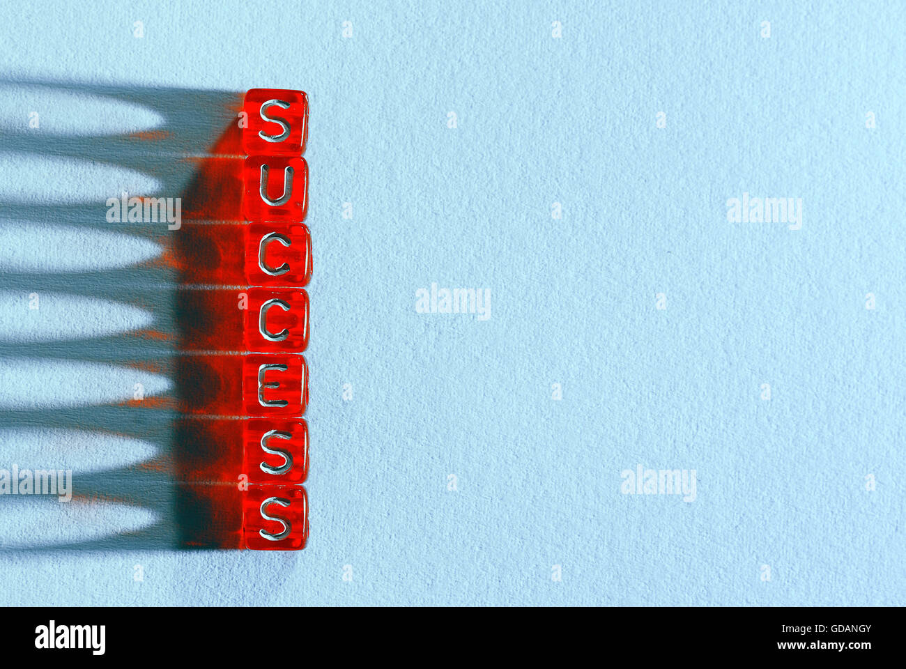 Erfolg, geschrieben am roten Würfel am blauen Papper Hintergrund und Lichtwirkung Stockfoto