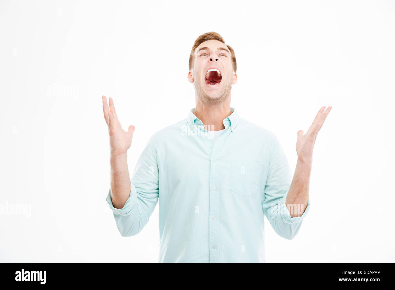 Wahnsinnig wütend junger Geschäftsmann mit erhobenen Händen schreien und blickte auf weißem Hintergrund Stockfoto