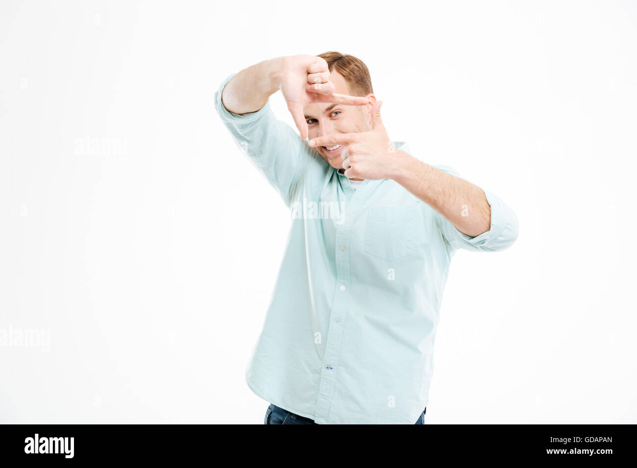 Lächelnd verspielte jungen Mann macht-Frame mit den Händen auf weißem Hintergrund Stockfoto