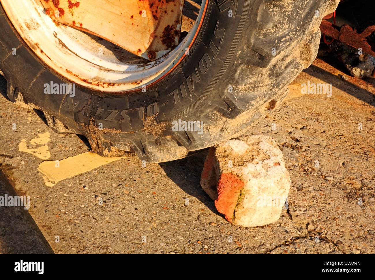 Ein Ziegel randvoll gegen ein Traktor-Rad auf einem Hang und Bewegung zu verhindern. Stockfoto