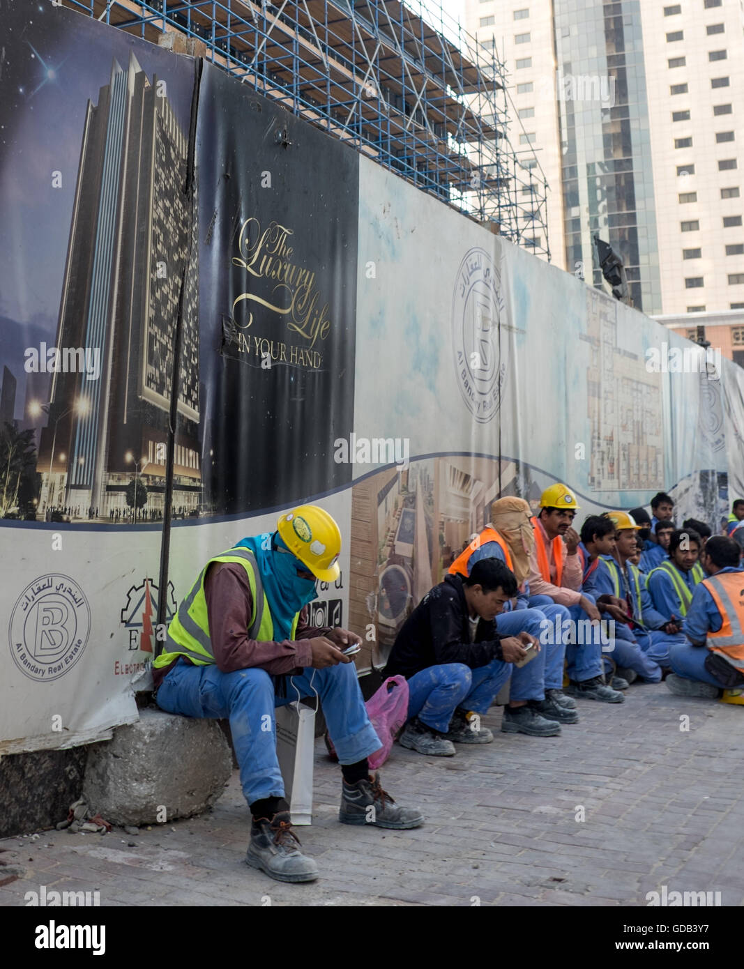 Bauarbeiter ruht in Doha, Katar. Plakat liest "The Luxury Life in Your Hands". Stockfoto