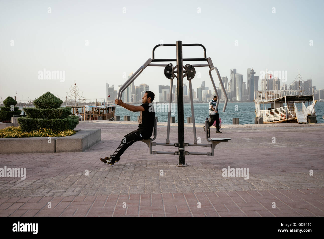 Wanderarbeitnehmer machen Verwendung von Trainingsgeräten auf Doha Corniche installiert. Stockfoto