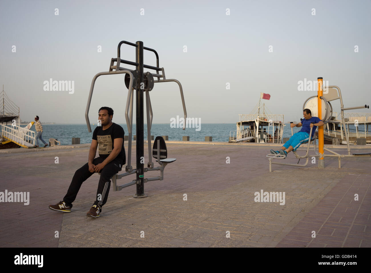Wanderarbeitnehmer machen Verwendung von Trainingsgeräten auf Doha Corniche installiert. Stockfoto