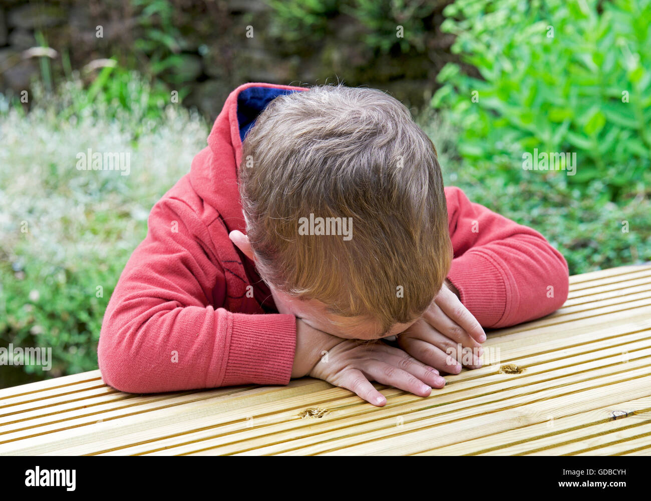 Junge, zwei Jahre alt, an einem Tisch sitzen und traurig Stockfoto