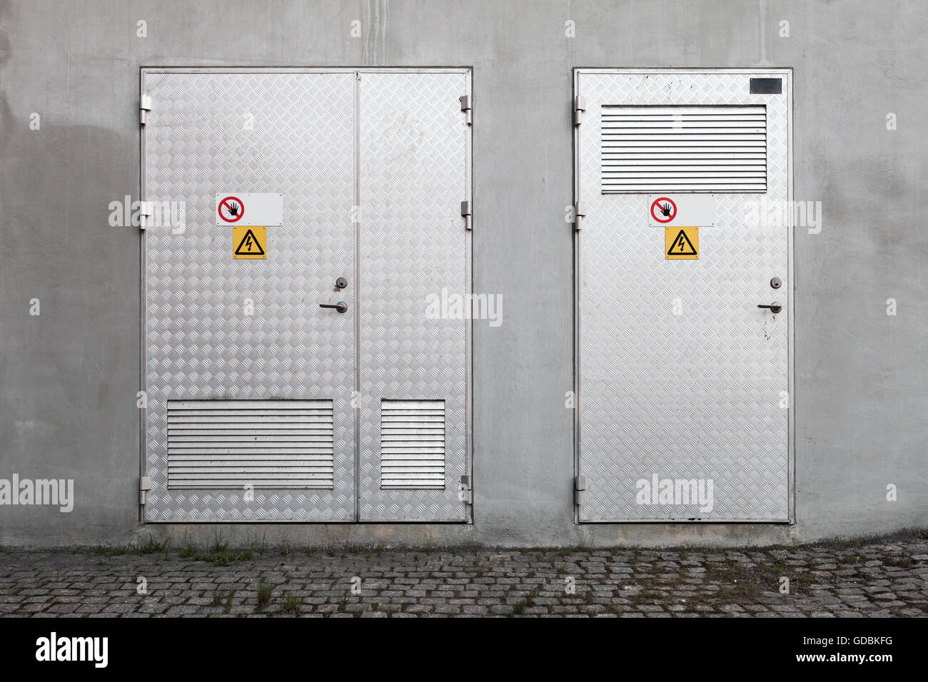 Metalltüren mit Hochspannung Warnschilder in graue Betonwand Industrie, Foto Hintergrundtextur, Vorderansicht Stockfoto