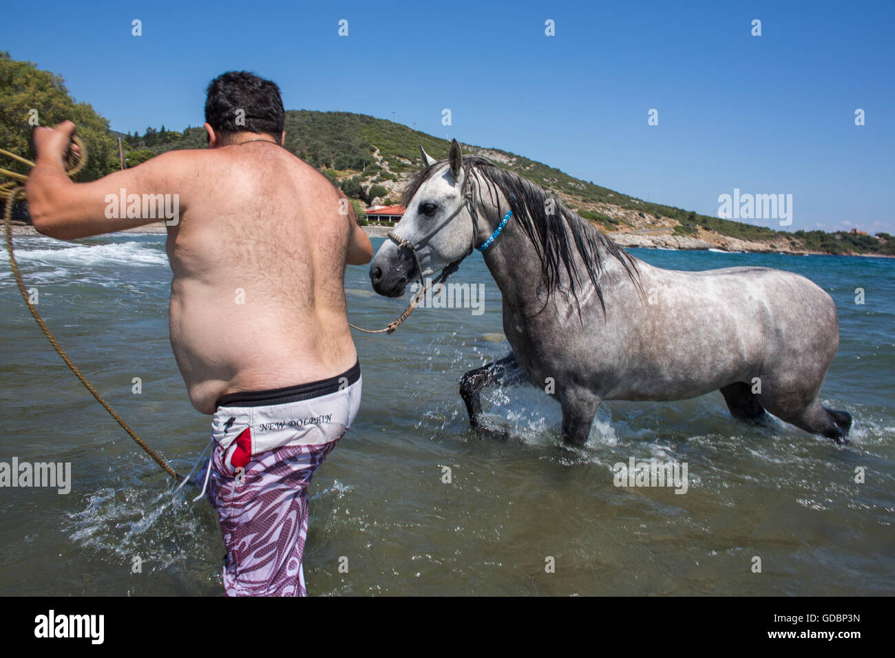 Griechischen Mann und sein Pferd nehmen ein Bad im Meer abkühlen lassen Stockfoto