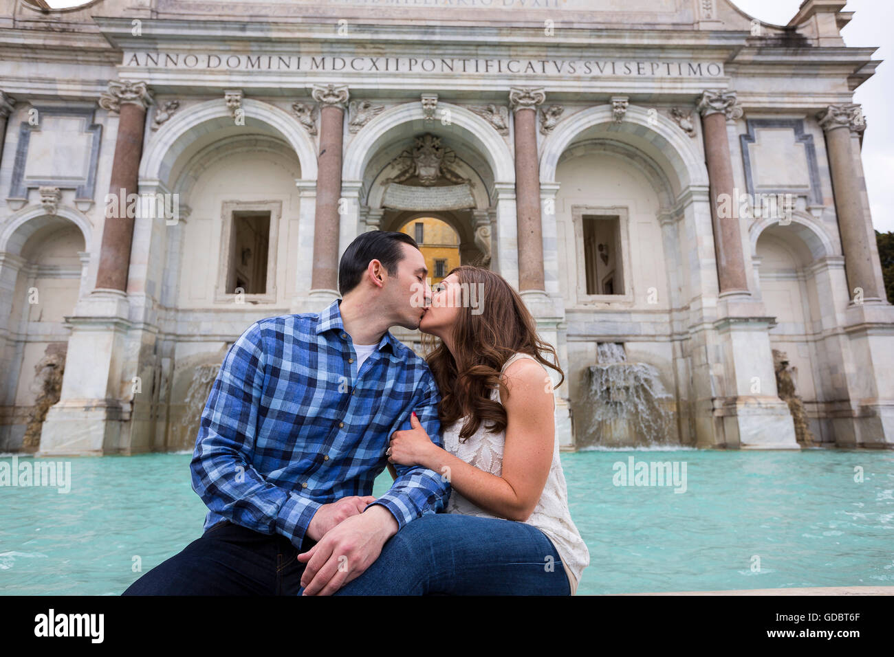 Paar küssen beim Sitzen auf dem Gianicolo-Wasser-Brunnen. Rom, Italien Stockfoto