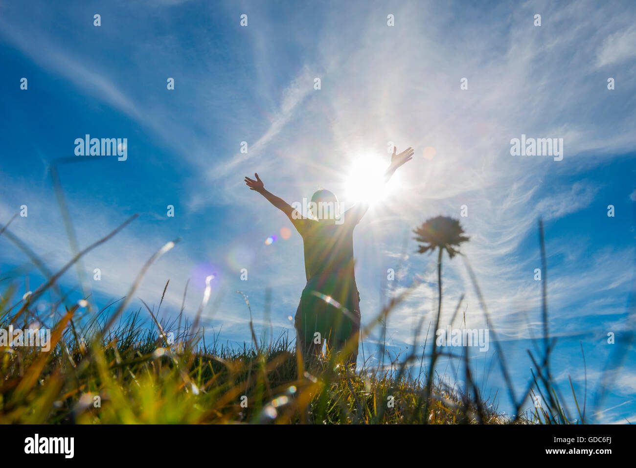 Frau mit erhobenen Armen und Sonnenschein und Rasen in Graubünden, Schweiz. Stockfoto
