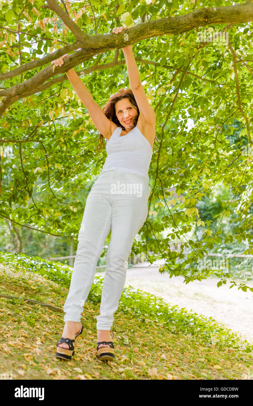 glückliche dralle Frau gekleidet in weißen schwingen von Ast in einem Garten Stockfoto