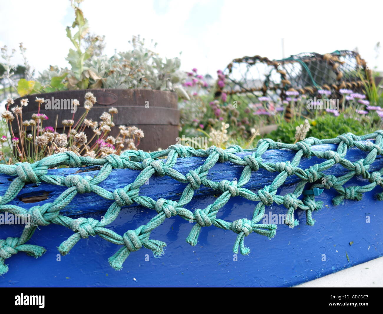 Ein altes Netz und blauen Boot als ein Übertopf für Blumen