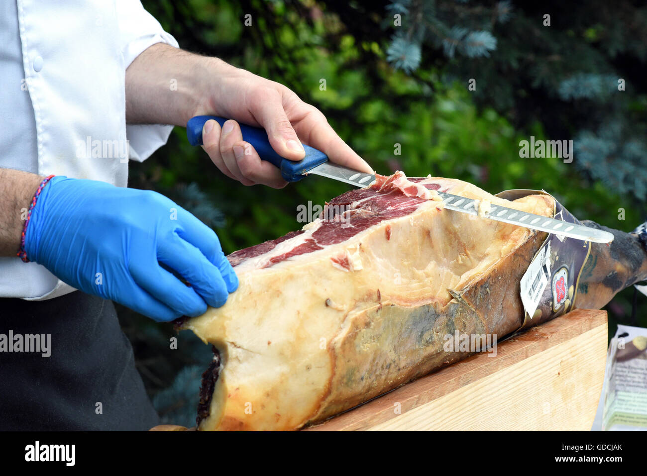 Koch oder Metzger schneiden eine Portion Fleisch von einem großen Schnitt mit einem langen Klinge Messer an ein Catering-Event oder Markt Stockfoto