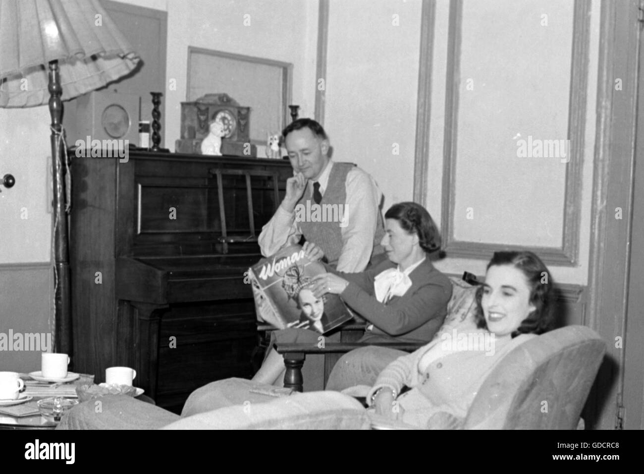 Typische Familie Wohnzimmer c1950. Mutter ist "Woman Magazine" lesen. Foto von Tony Henshaw Stockfoto