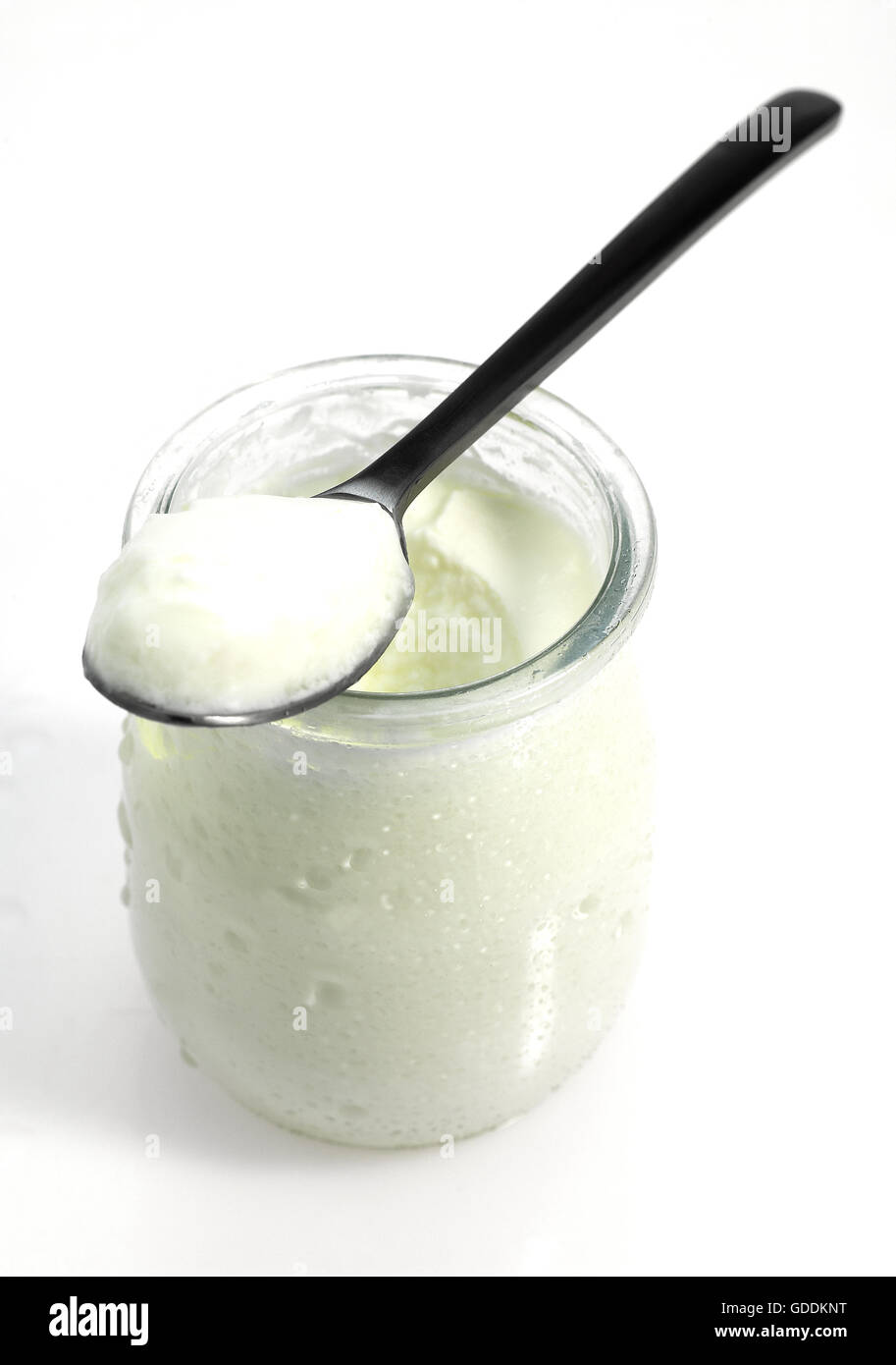 Tee-Löffel und Glas Naturjoghurt vor weißem Hintergrund Stockfoto