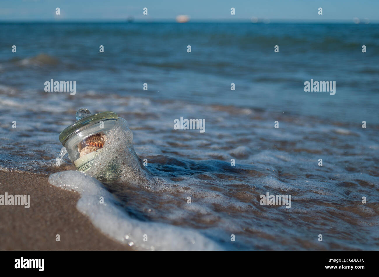 in den Sand in der Brandung ist das Glasgefäß mit Geld und Muscheln,  Geschenk Stockfotografie - Alamy