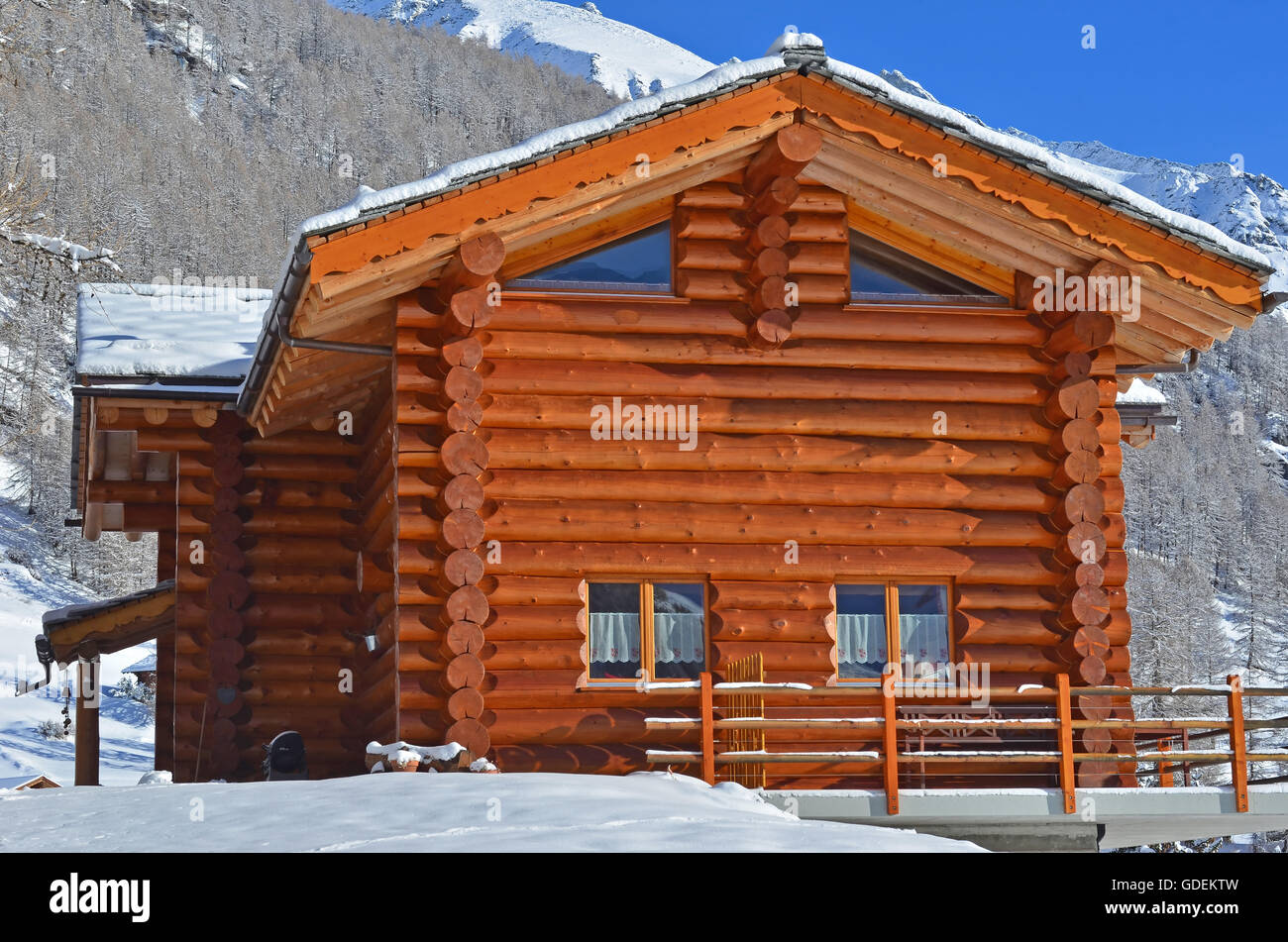 Eine alpine Blockhütte mit Schnee bedeckt, Berge und Wälder im Hintergrund Stockfoto