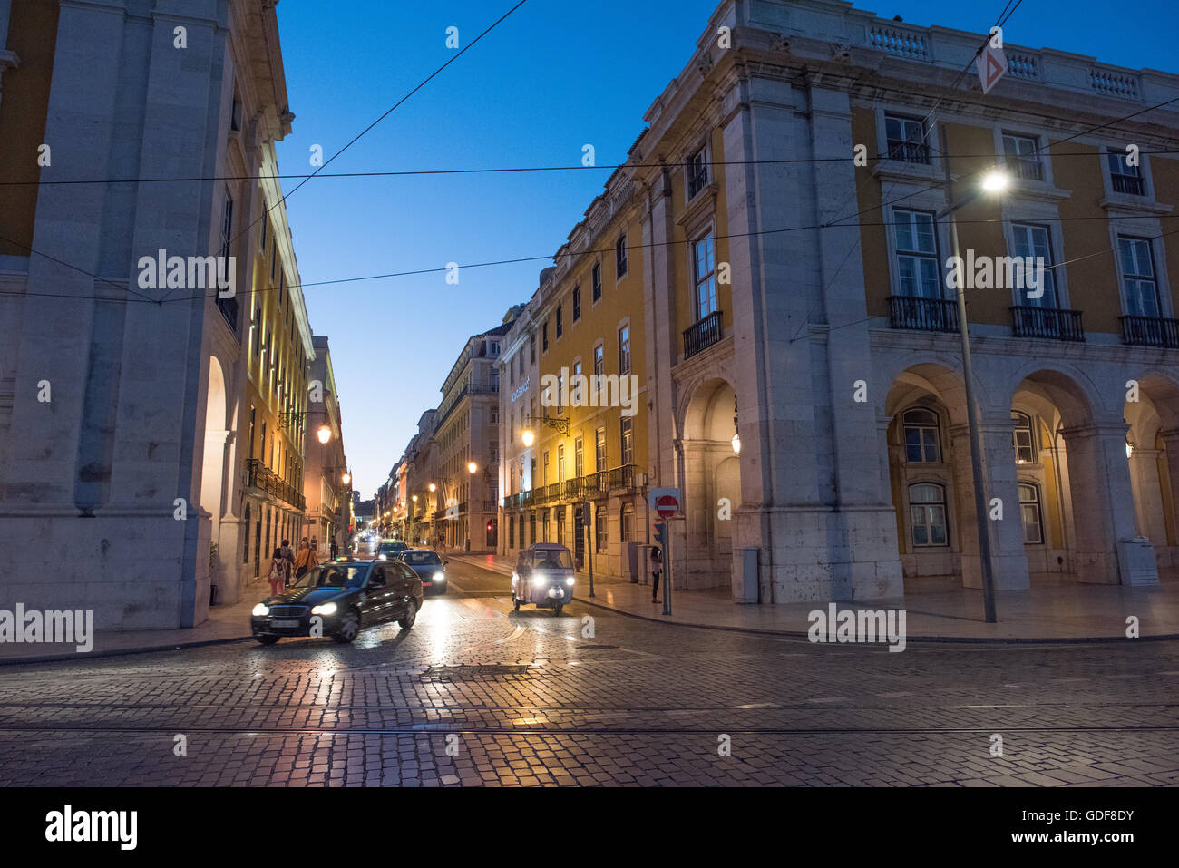 Pombaline Architecture Sidestreet Lissabon Portugal // LISSABON, Portugal – Eine charmante Seitenstraße zweigt von Prac do Comércio (Handelsplatz) im historischen Stadtteil Baixa ab. Die Straße zeigt typische Architektur im pombalinischen Stil mit ihren einheitlichen Fassaden, schmiedeeisernen Balkonen und gefliesten Wänden. Dieses Gittermuster, das charakteristisch für die Stadtplanung des Gebiets aus dem 18. Jahrhundert ist, bietet einen Einblick in den Wiederaufbau von Lissabon nach dem Erdbeben und das tägliche Stadtleben. Stockfoto