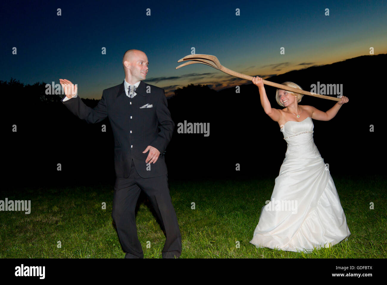Glückliche Braut und Bräutigam stehend in einem Feld in der Dämmerung, Braut, den Bräutigam mit der Heugabel zu necken Stockfoto