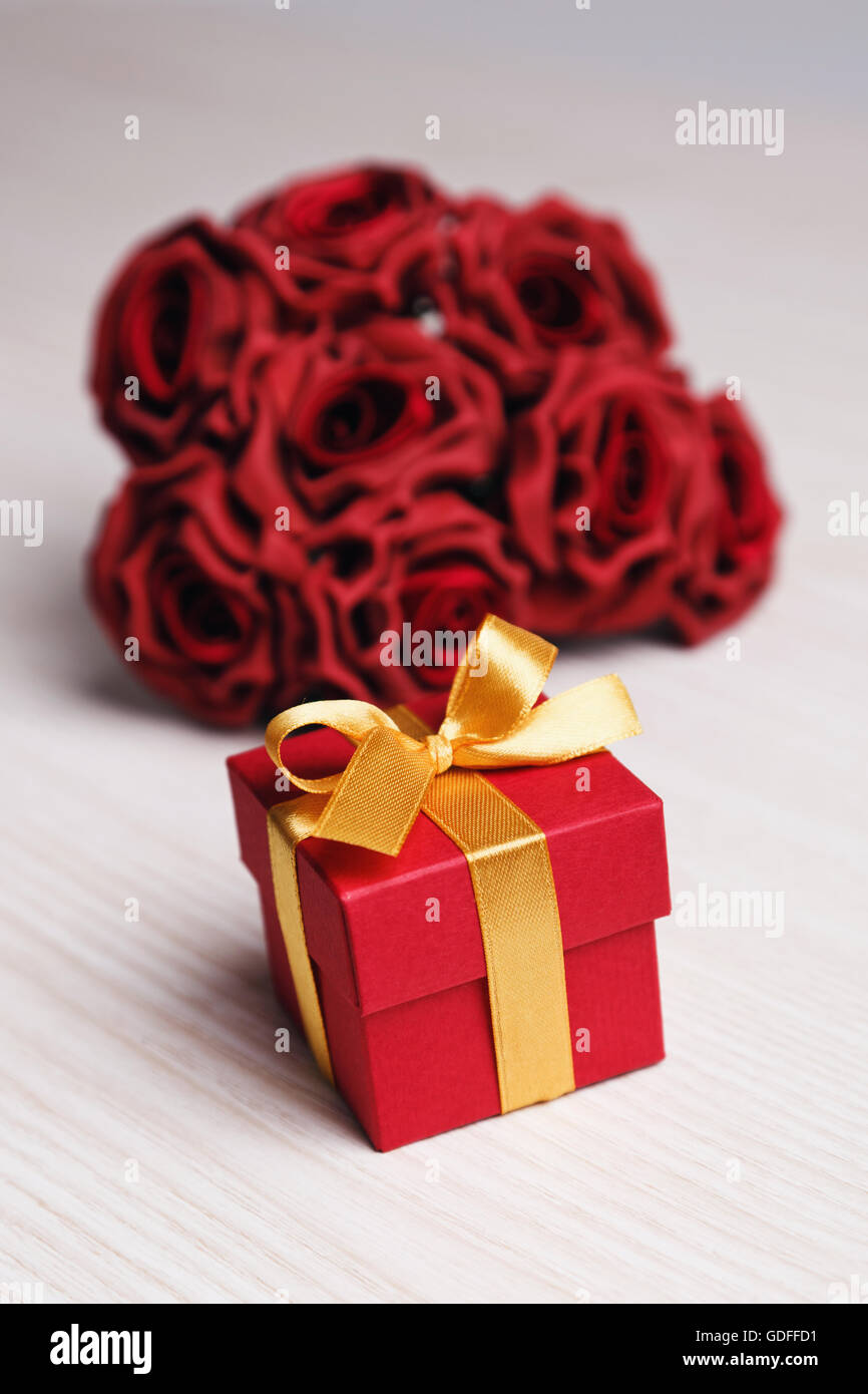 Rote Blumen und Geschenk-Box mit gelben Band Stockfoto