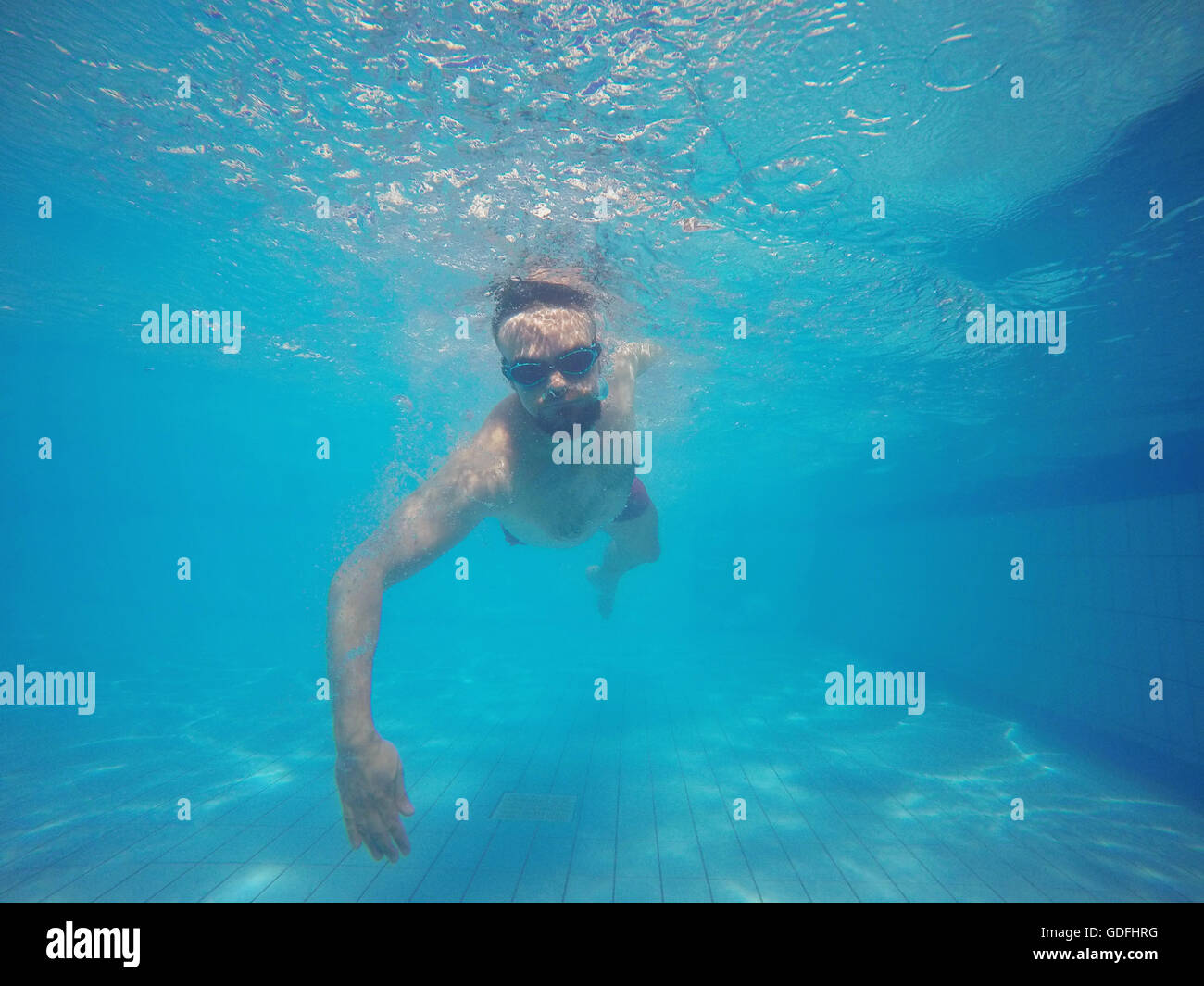 Junger Bart Mann mit Brille unter Wasser im Pool schwimmen Stockfoto