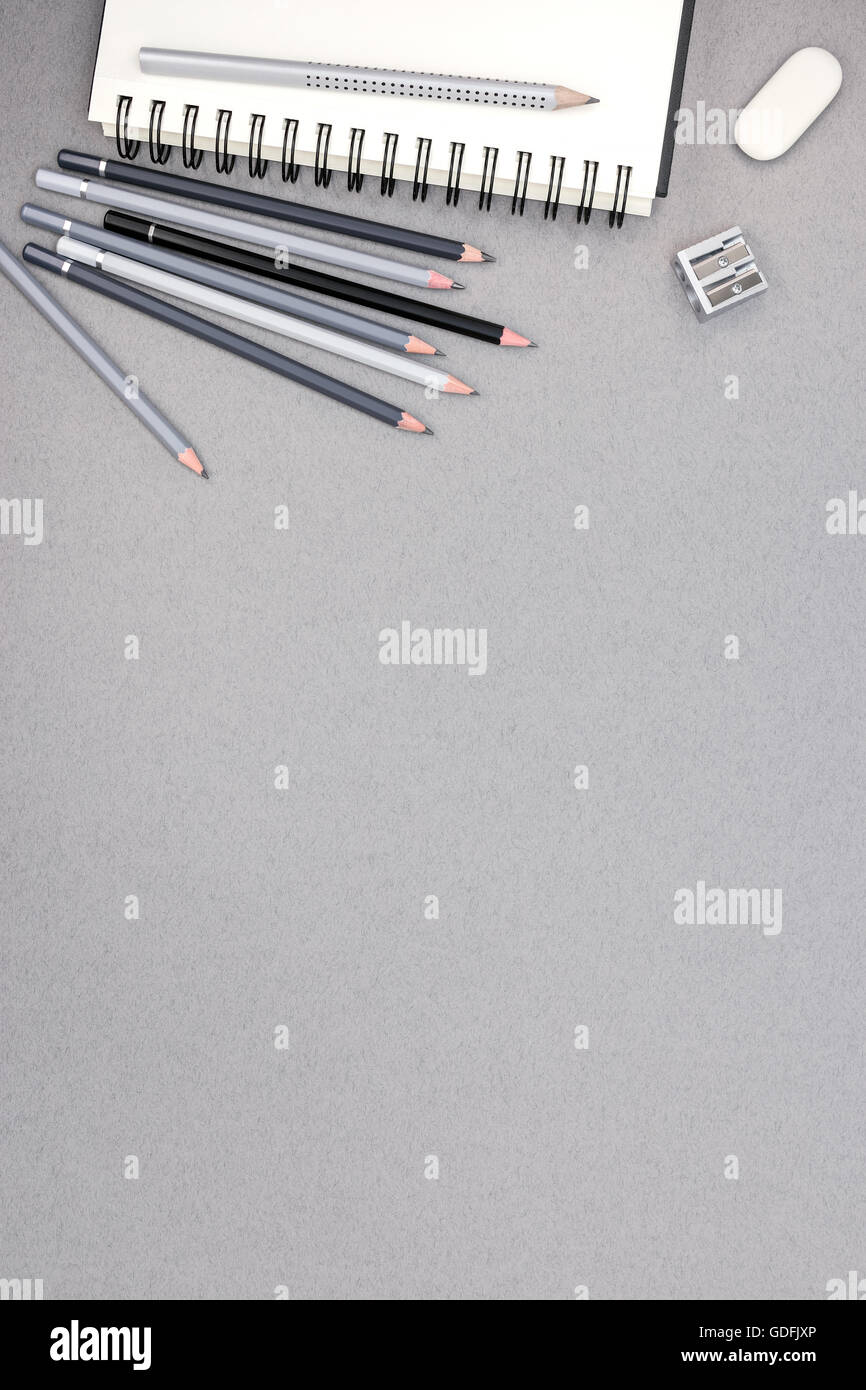 Spiral-Notizbuch, Bleistifte, Radiergummi, Spitzer auf grauen Recyclingpapier Hintergrund, Ansicht von oben Stockfoto