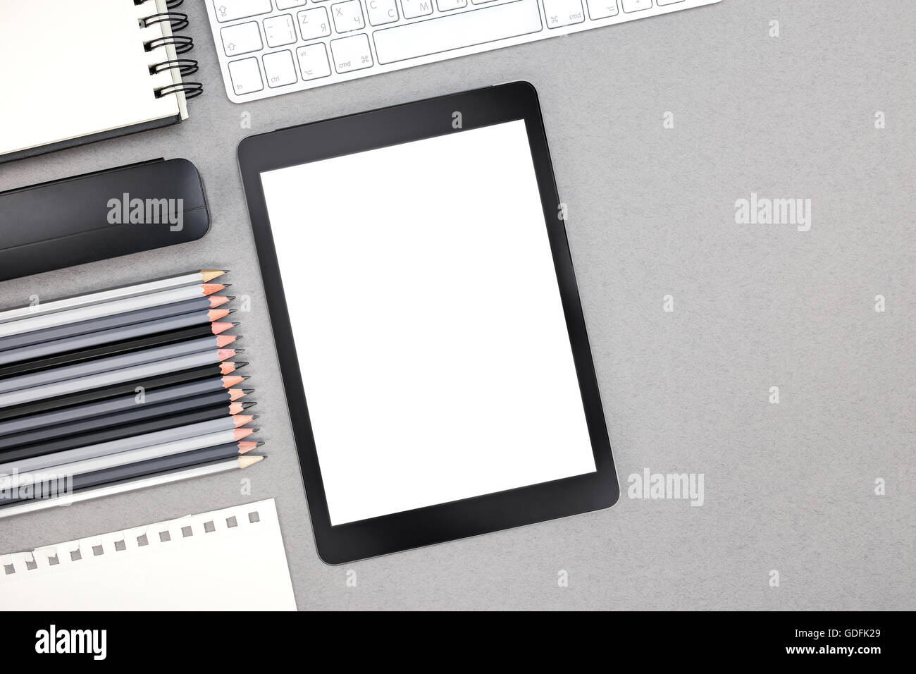 Blick von oben auf grauen Bürotisch mit Spiral-Notizblock, Tastatur, Tablet-Computer, Bleistifte Stockfoto