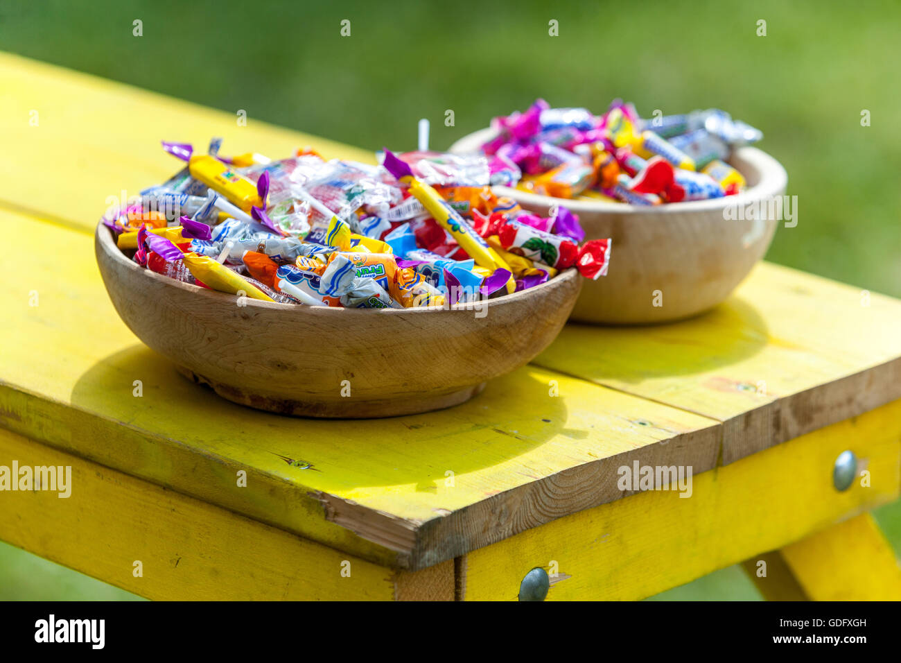 Eingewickelte Süßigkeiten, Süßigkeiten in einem Korb, Holzschale auf dem Tisch, über Essen Stockfoto