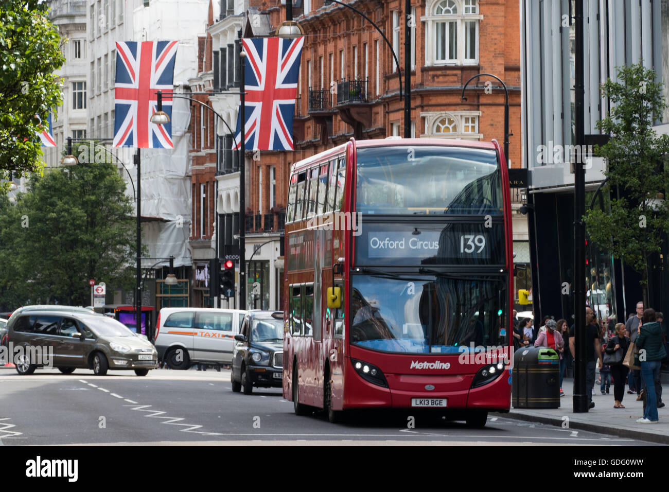 Typischen roten Doppeldecker-bus im Zentrum von London mit Großbritannien Flaggen im Hintergrund Stockfoto