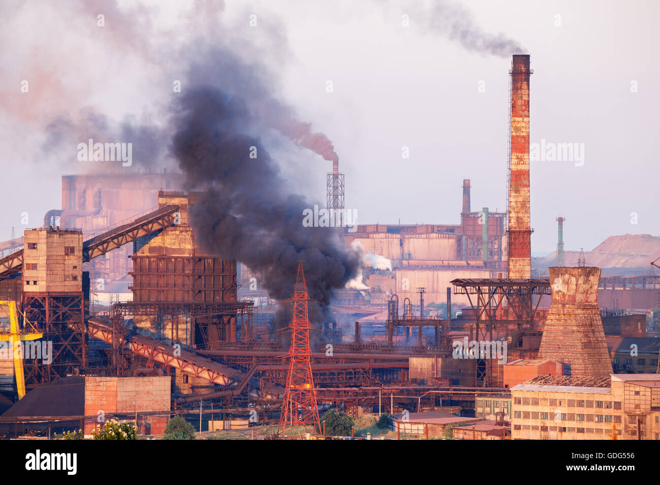 Industrielandschaft in der Ukraine. Stahlwerk mit Smog bei Sonnenuntergang. Rohre mit Rauch. Metallurgische Fabrik. Stahlwerke, Eisenwerk Stockfoto