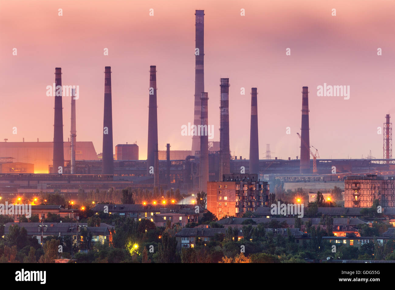 Gebäude der Stadt auf dem Hintergrund der Stahlfabrik mit Schornsteine in der Nacht.  Metallurgische Fabrik mit Kamin. Stahlwerke, Eisen Stockfoto