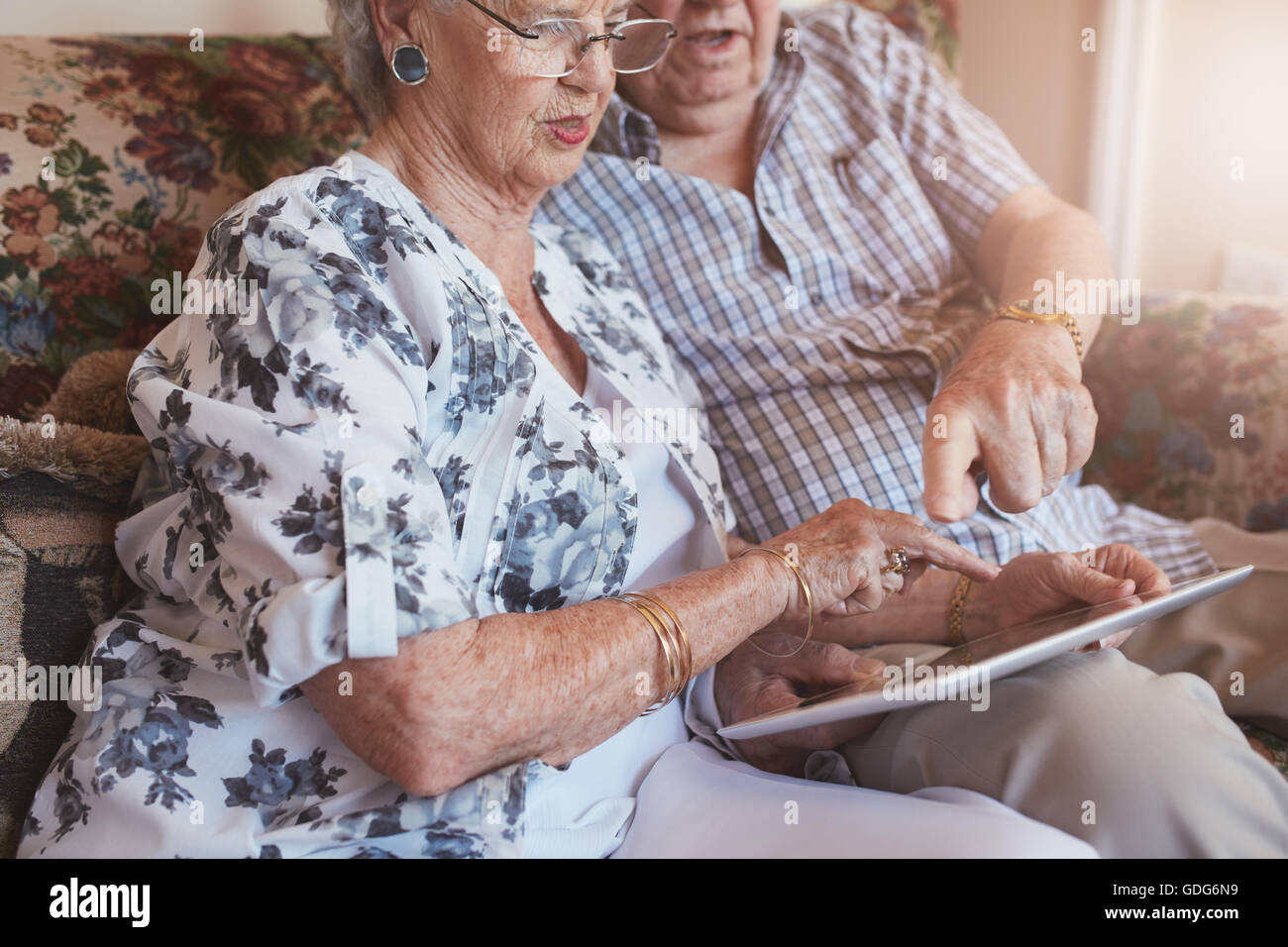 Schuss von Ehepaar im Ruhestand zu Hause hautnah mit digital-Tablette. Ältere Mann und Frau sitzen zusammen auf couch zu Hause mit einem touc Stockfoto