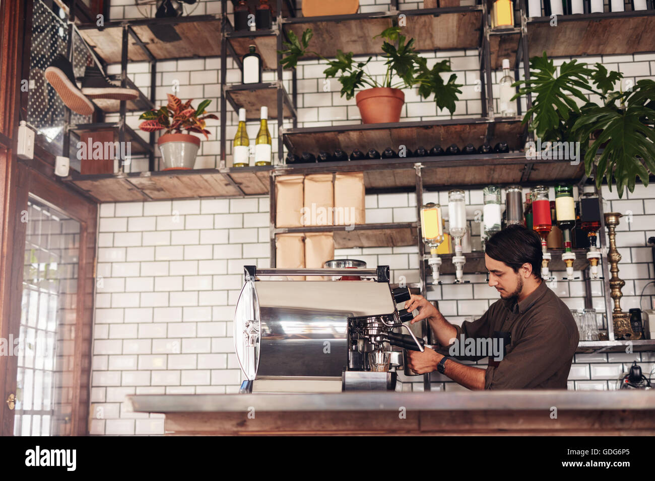 Richtungskontrolle Ansicht der männlichen Barista eine Tasse Kaffee zu machen. Junger Mann hinter der Café Zähler bereitet Kaffee mit Kaffee Stockfoto