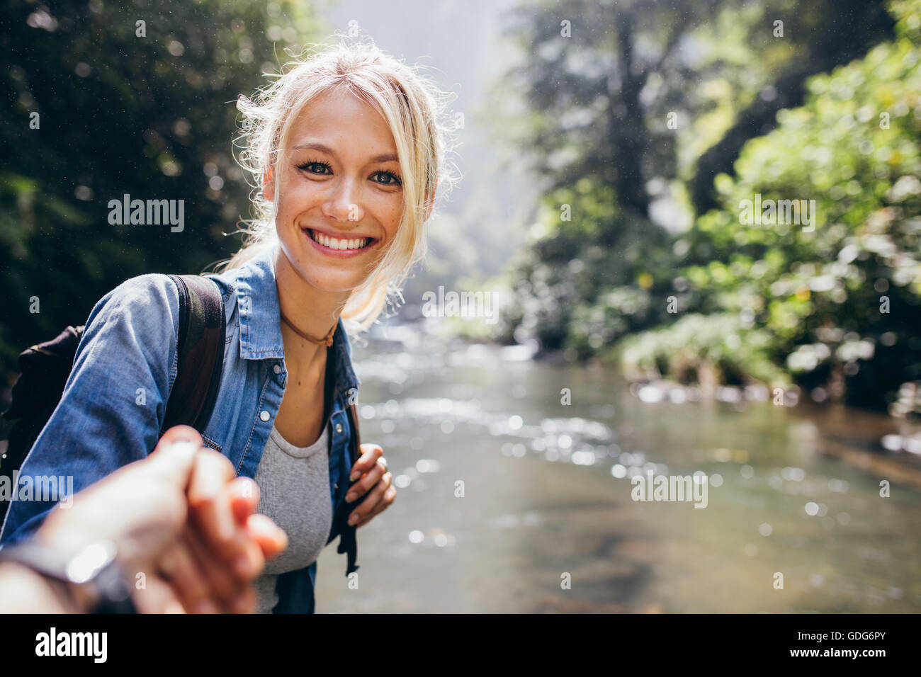 Porträt der glückliche junge Frau, die an Hand von ihrem Freund bei einem Spaziergang durch den Wald Creek. Genießen Sie eine Wanderung in der Natur mit Frau Stockfoto