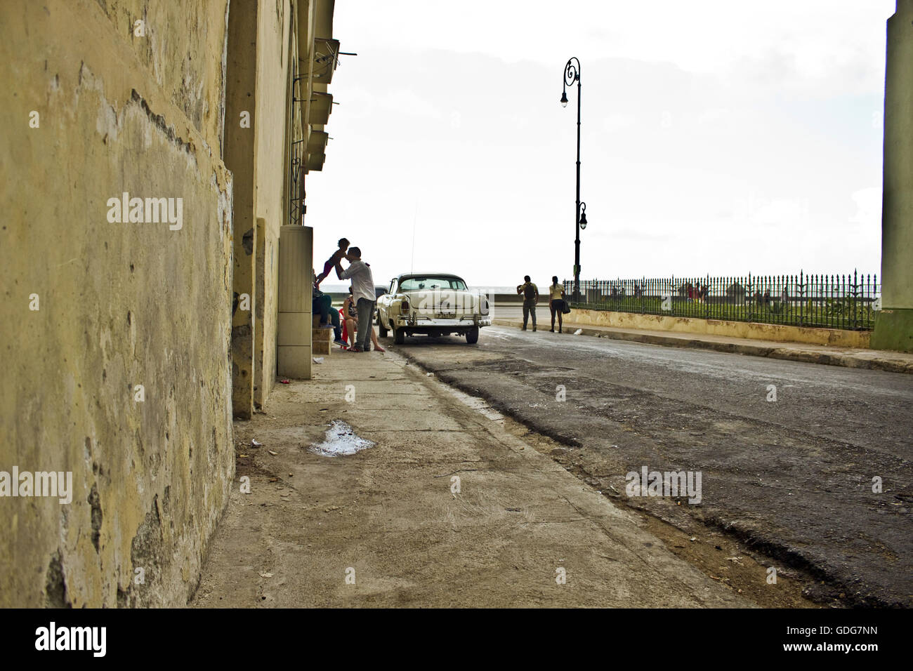 Straßenszene in Havanna, Kuba mit einem Oldtimer und ein Mann hält ein Baby. Stockfoto