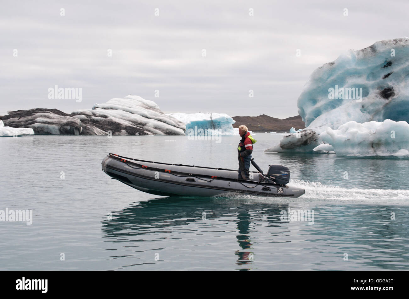 Island: Mann auf einer Jolle unter dem Eis, Eisberge in der Gletscherlagune Jökulsárlón, ein Gletschersee im Vatnajökull-Nationalpark Stockfoto