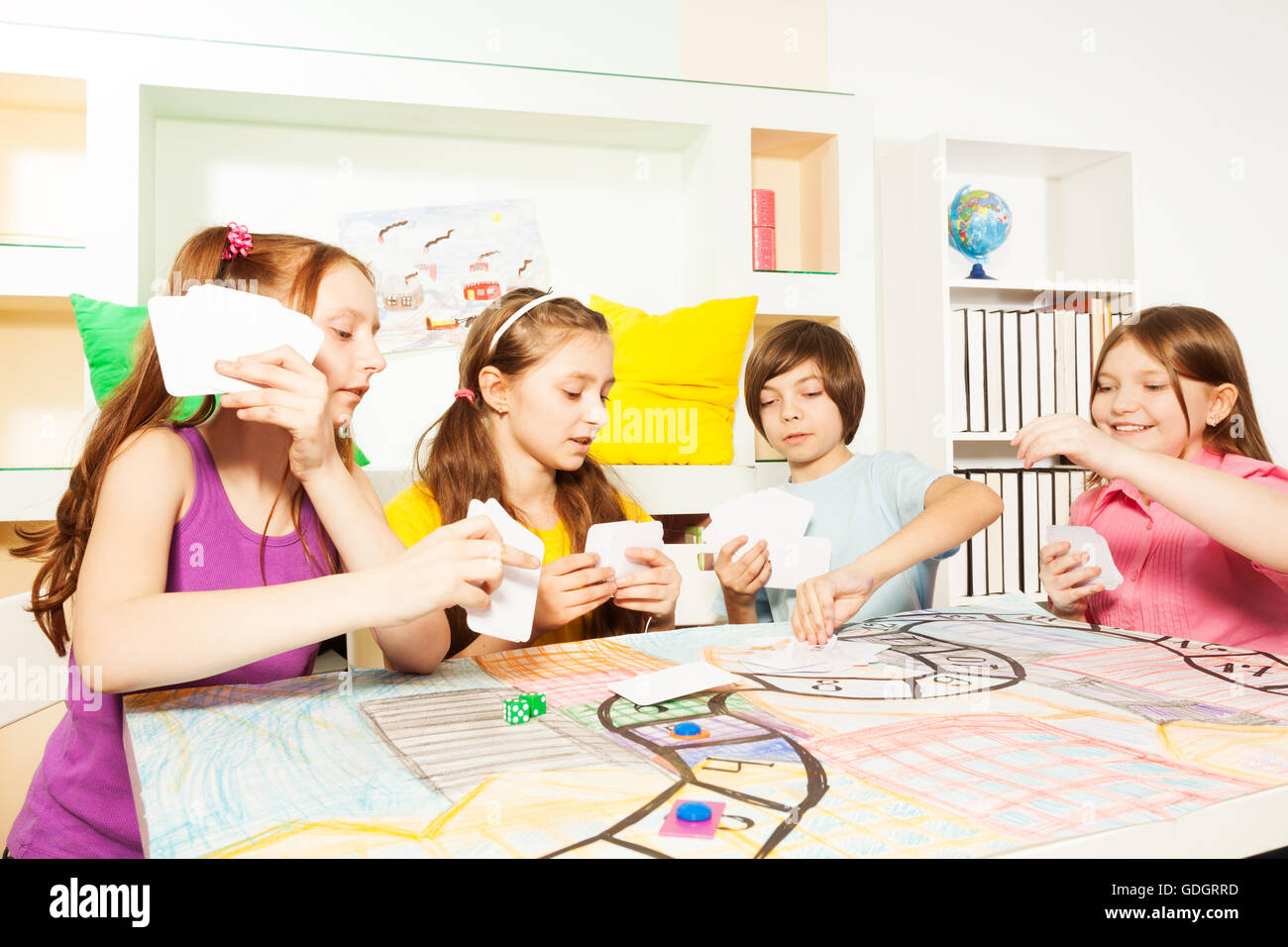 Vier Freunde, die das Tabletop-Spiel mit Karten spielen Stockfoto