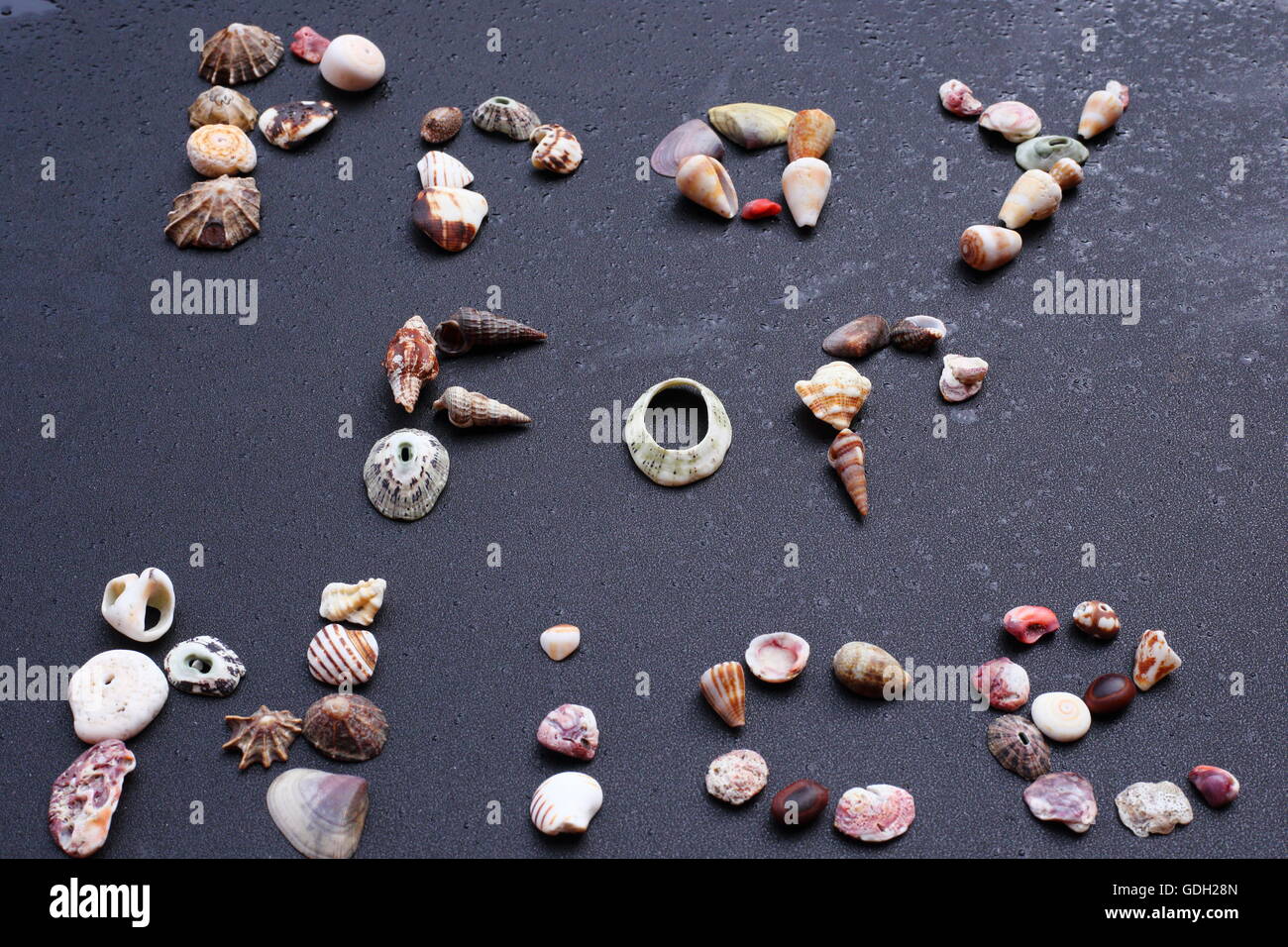 Die Worte beten für schön geschriebene in Muscheln vor schwarzem Hintergrund Stockfoto