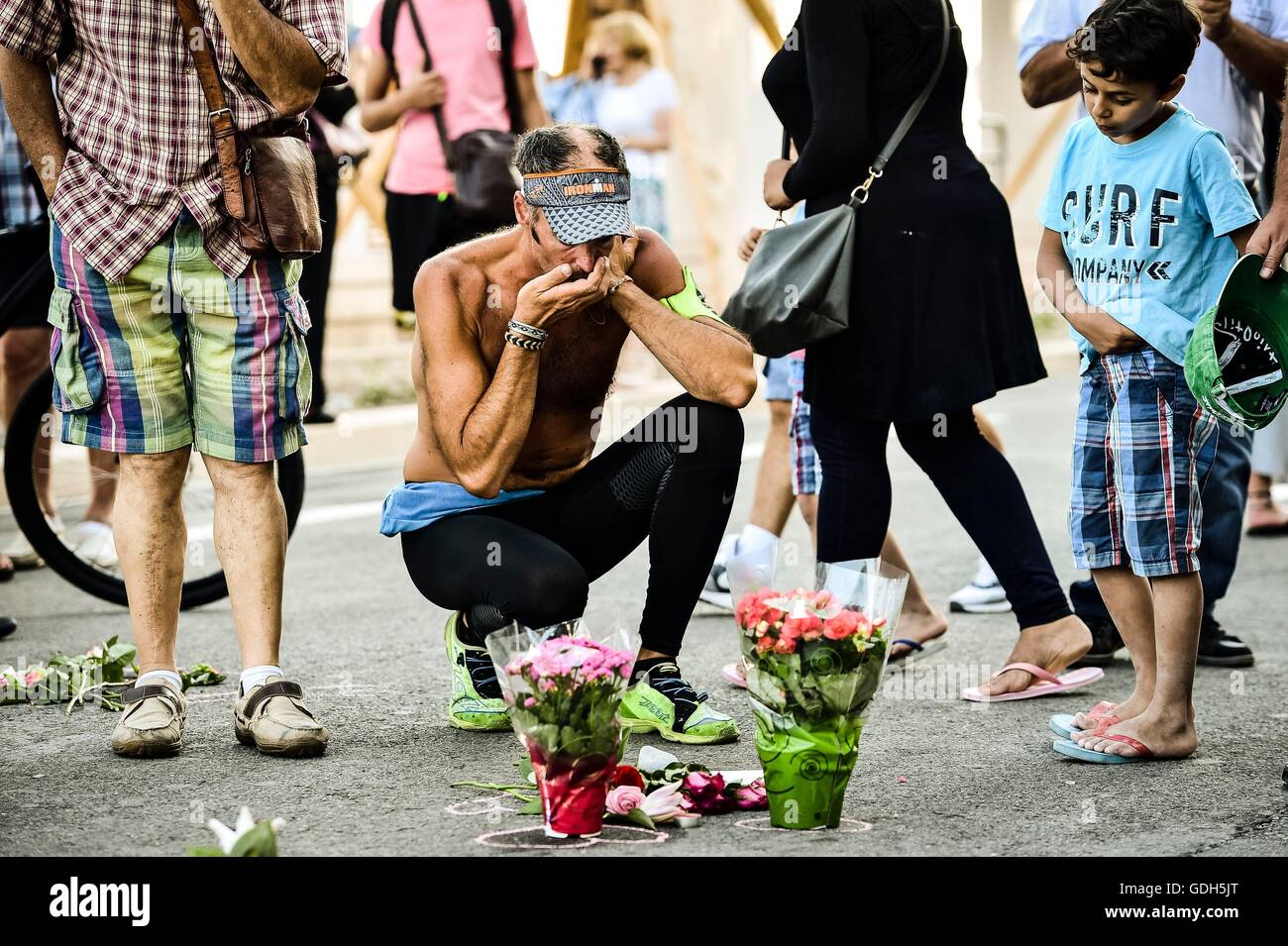 Ein Mann reagiert wie kniet er vor floral Tribute wo Körper auf der Promenade des Anglais, Nizza fiel, als französische Detektive versuchen werden, die Umstände zusammenzusetzen, die mindestens 84 Menschen tot verließ und Noten nach einem Terroristen absichtlich verletzt einen LKW in Meuterei auf der Feiernden, fuhr bevor er in eine Pattsituation mit bewaffneten Polizisten tödlich verwundet. Stockfoto