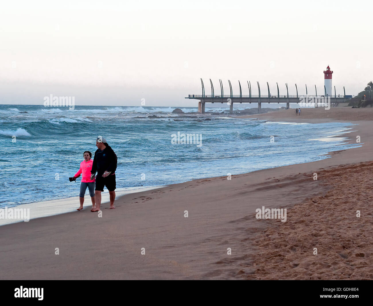 DURBAN, Südafrika - 11. Juli 2016: Menschen am Strand von Umhlanga Rocks, mit dem Millennium Pier und dem Leuchtturm in den Rücken Stockfoto