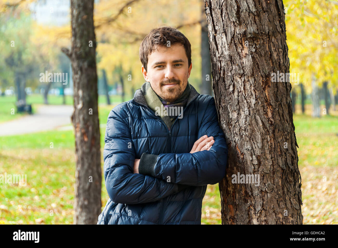 Hübscher Kerl lehnte sich gegen einen Baum im Herbst park Stockfoto