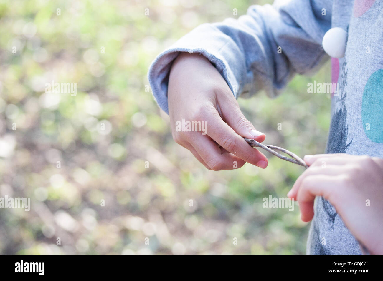 Mädchen spielt mit Zweigen, die mit ihren Händen Stockfoto