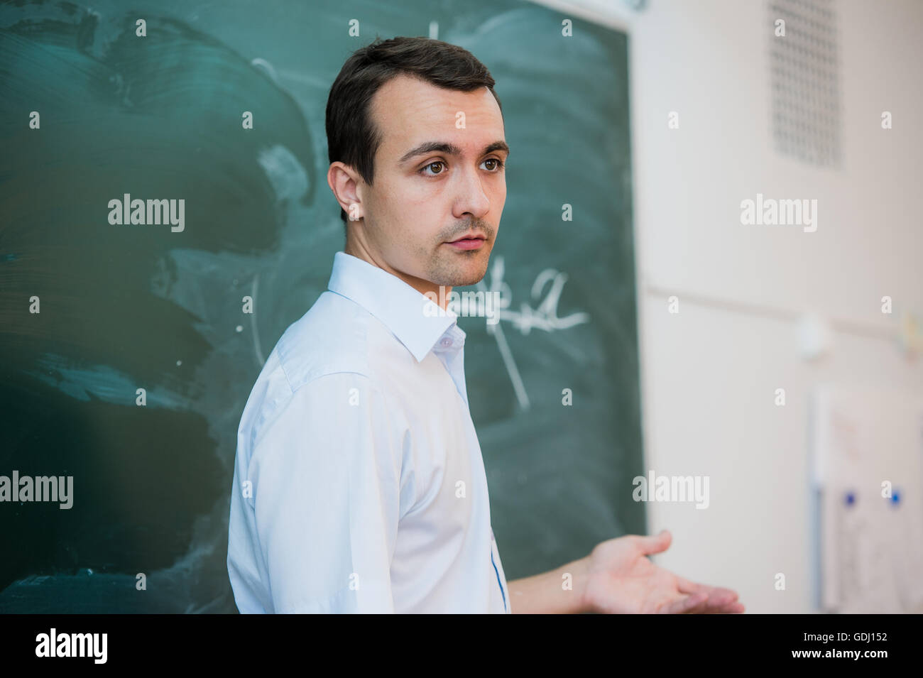Junge Lehrer oder Schüler zeichnen an einer Tafel mit Formel Dreieck Stockfoto