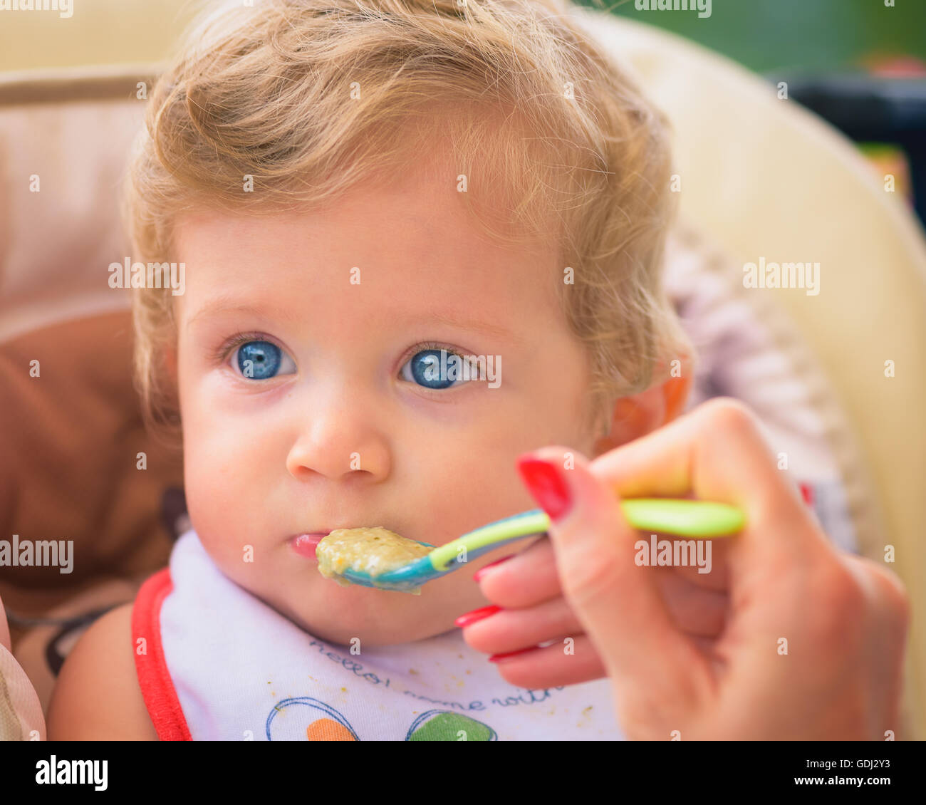 Eine Mutter füttert ihr Baby Boy mit Löffel im Freien. Stockfoto