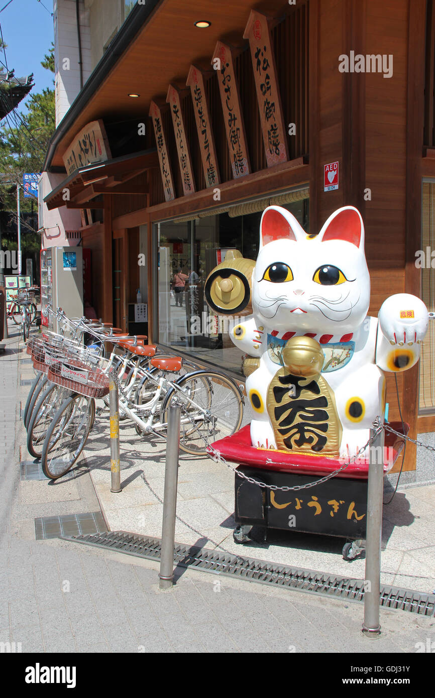 Maneki-Neko und Fahrräder geparkt vor einem Restaurant in Amanohashidate (Japan). Stockfoto