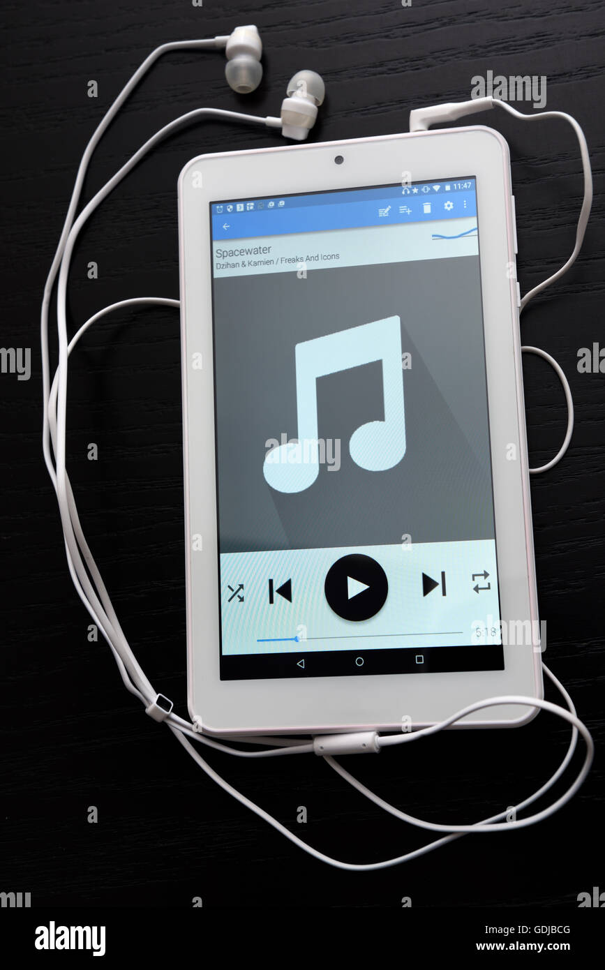 Tablet mit Ohrhörer Musik auf einem schwarzen Tisch Stockfoto