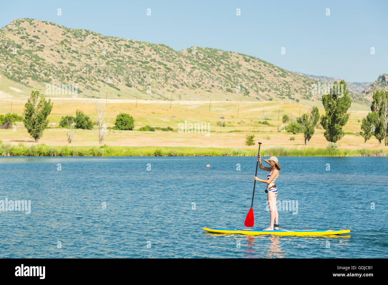 Junge Frau lernen wie man Paddleboard am kleinen Teich Stockfotografie