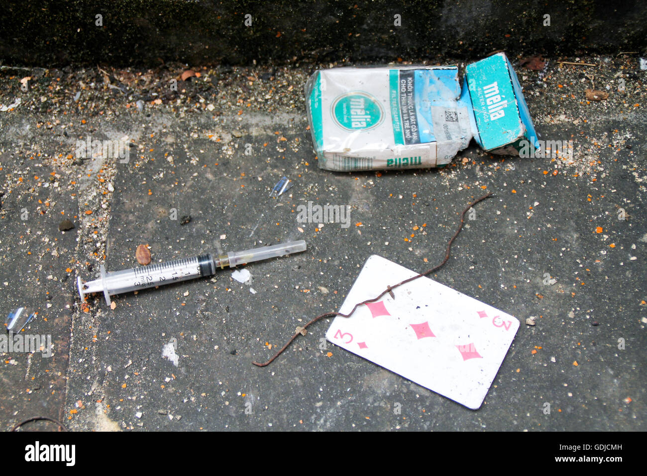 Nadel und Spritze mit Zigarettenschachtel in schmutzige Straße Ecke. Drug User treff Stockfoto