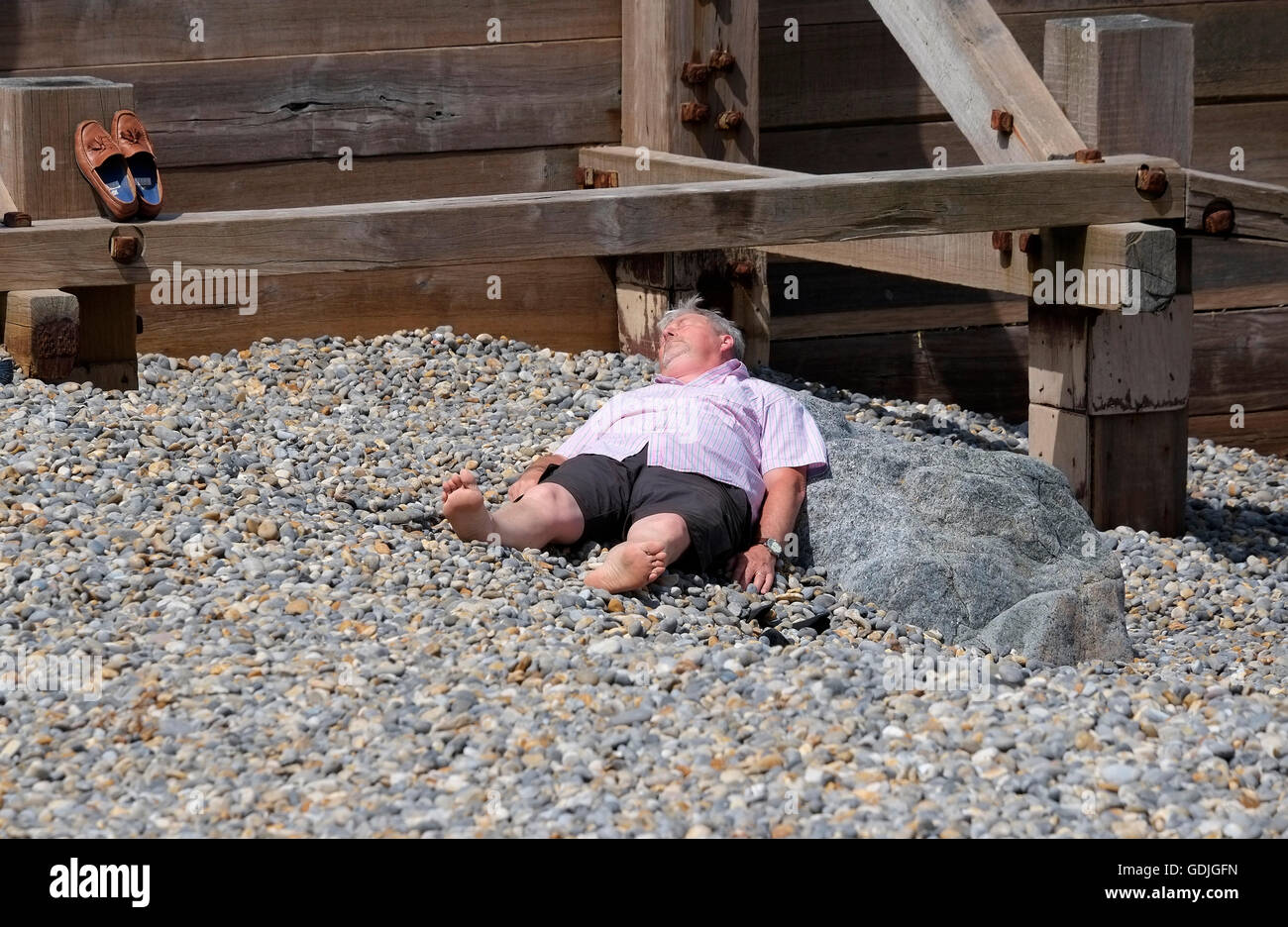 reifer Mann Handauflegen Sheringham Kiesstrand Stockfoto