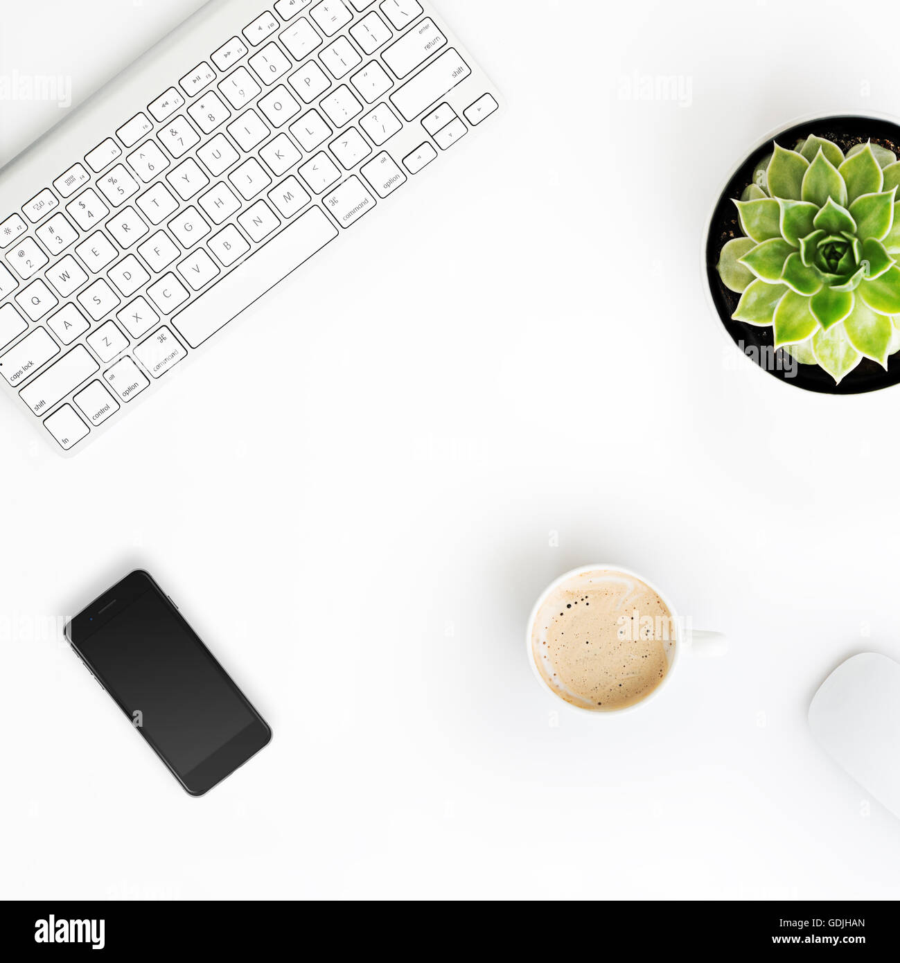 Weißer Schreibtisch Bürotisch mit drahtlosen Aluminium Tastatur, Tasse Kaffee, Smartphone mit schwarzer Bildschirm, Maus und saftigen flowe Stockfoto