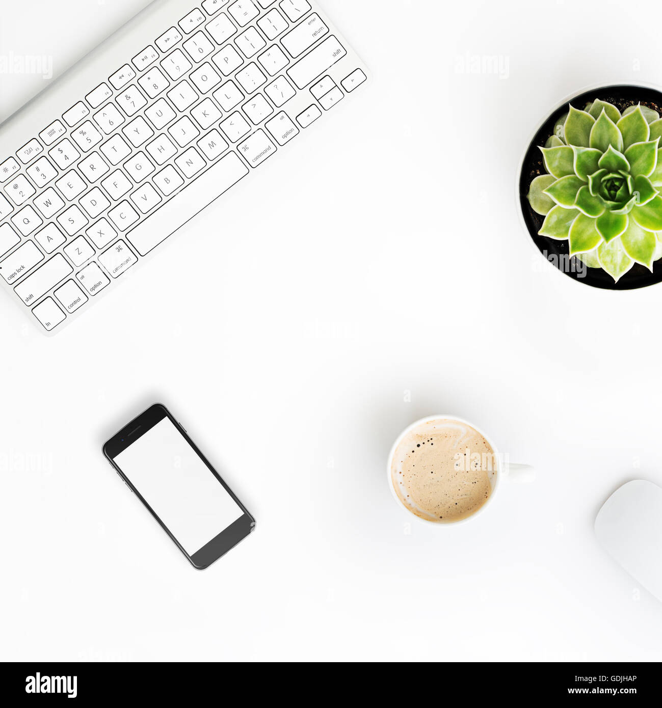 Weißer Schreibtisch Bürotisch mit drahtlosen Aluminium Tastatur, Tasse Kaffee, Smartphone mit leerer Bildschirm, Maus und saftigen flowe Stockfoto