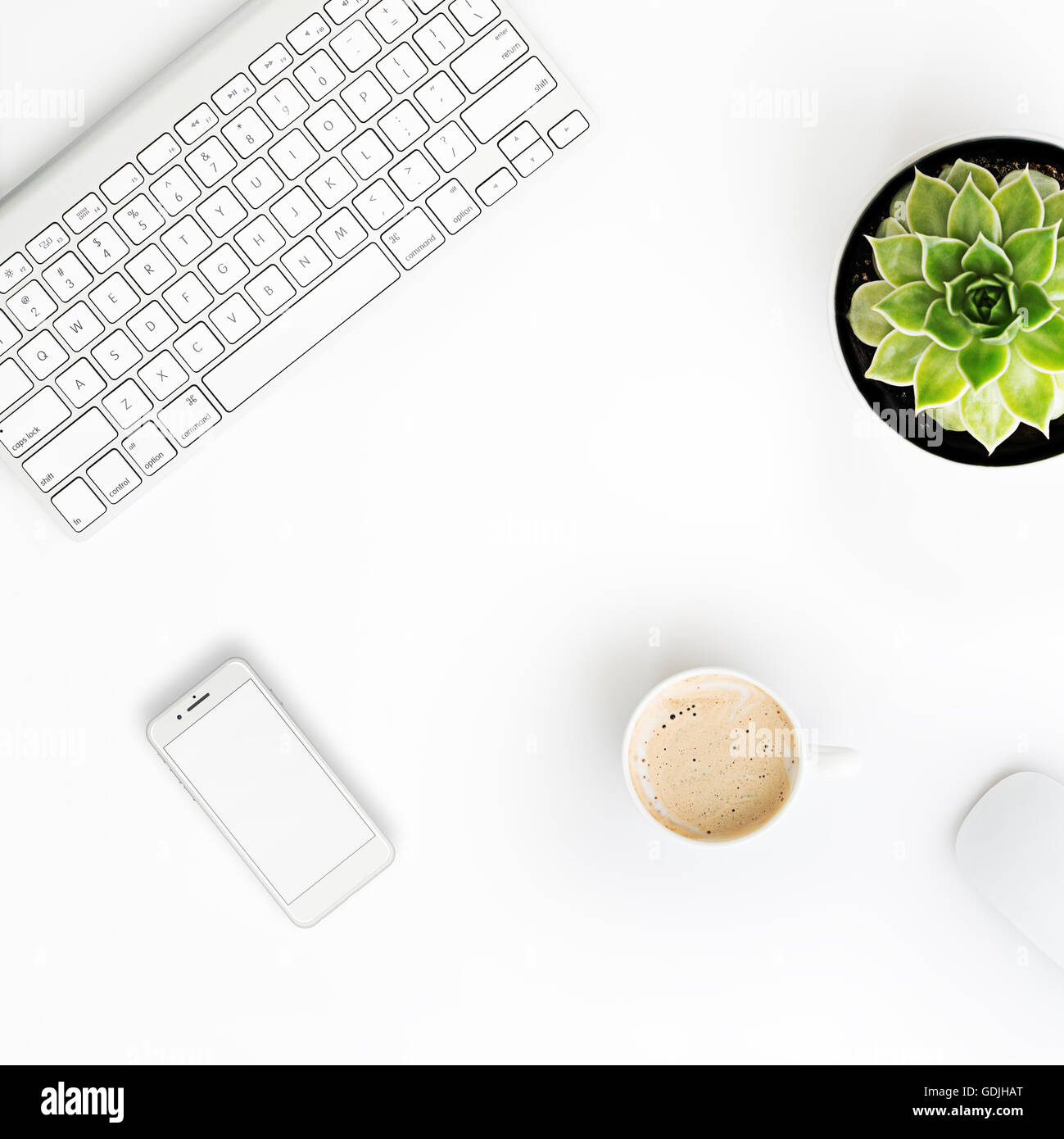 Weißer Schreibtisch Bürotisch mit drahtlosen Aluminium Tastatur, Tasse Kaffee, Smartphone mit leerer Bildschirm, Maus und saftigen flowe Stockfoto